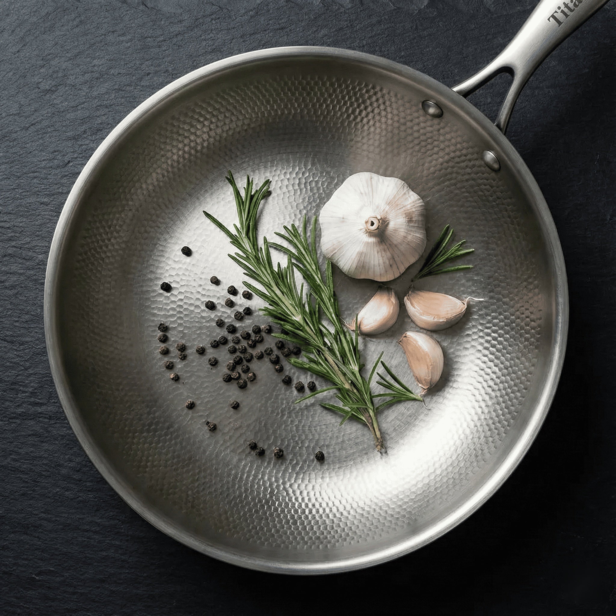 Pfanne aus reinem Titan TitaniumCook 26 cm, Draufsicht, mit Knoblauch, Rosmarin und Pfefferkörnern